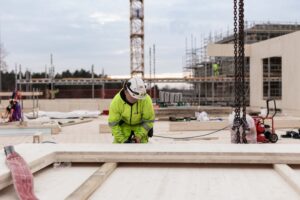 Mann arbeider med massivtre på byggeplass