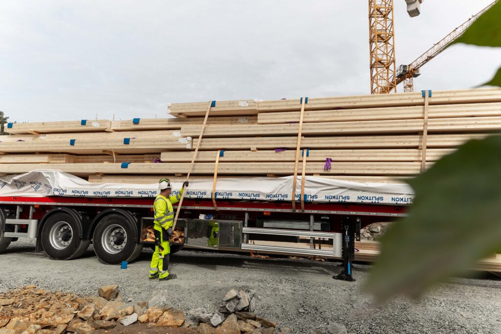 Mann står foran henger med massivtre